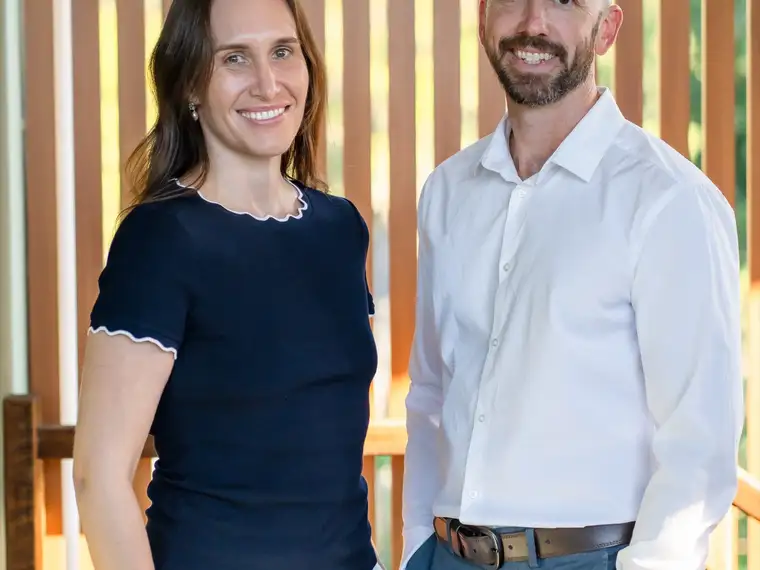 Two Grove Support Services support workers standing together in front of a timber screen