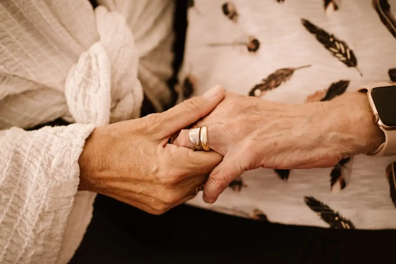 Two people holding hands in a warm indoor setting