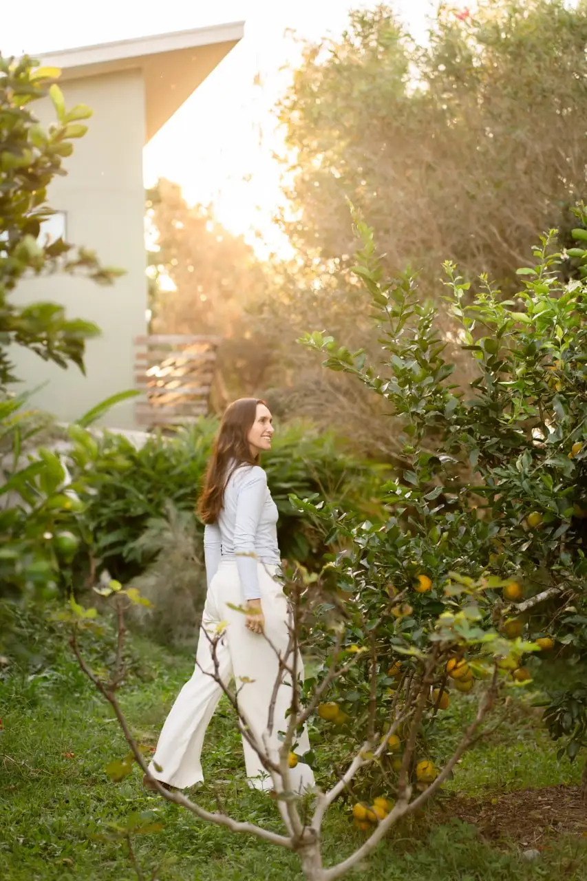 A woman walking through a sunlit garden