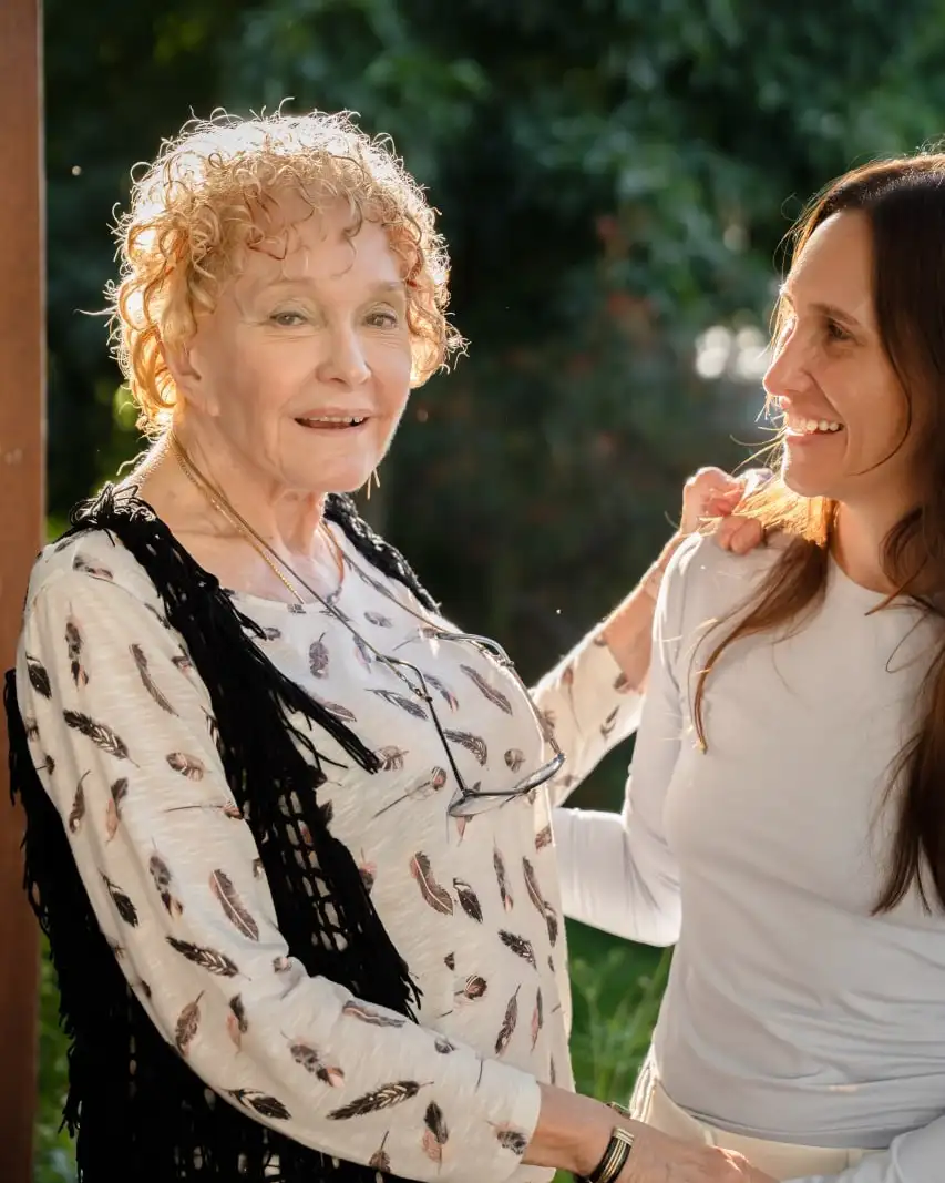 A support worker and an older woman walking together in golden sunlight