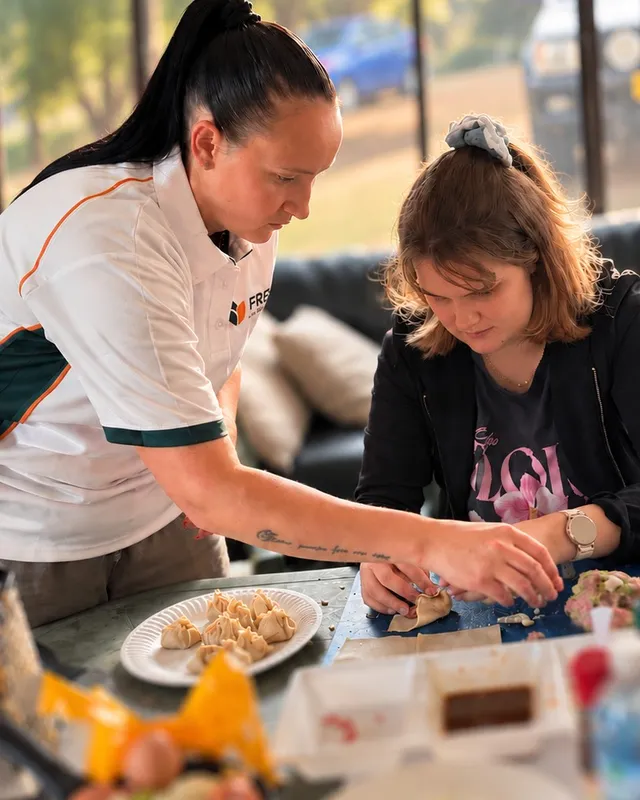 Two people preparing and folding dumplings together in a kitchen
